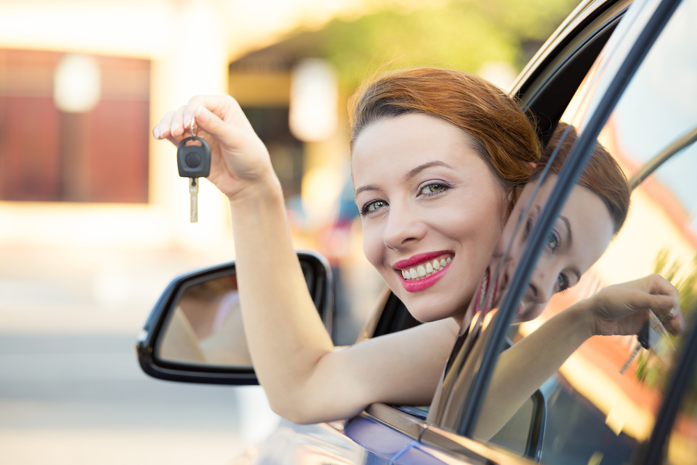 Closeup portrait happy, smiling, young attractive woman, buyer sitting in her new blue car showing keys isolated outside dealer, dealership lot, office. Personal transportation, auto purchase concept Closeup portrait happy, smiling, young attractive woman, buyer sitting in her new blue car showing keys isolated outside dealer, dealership lot, office. Personal transportation, auto purchase concept